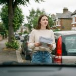 Jeune femme avec documents d'assurance près d'une voiture