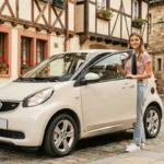 Femme tenant des clés devant une voiture sans permis garée dans une rue pavée du centre historique de Bayonne