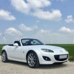 white porsche 911 on green grass field under blue sky during daytime