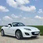white porsche 911 on green grass field under blue sky during daytime