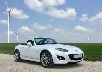 white porsche 911 on green grass field under blue sky during daytime