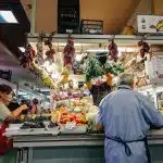 woman in white dress standing in front of vegetable display