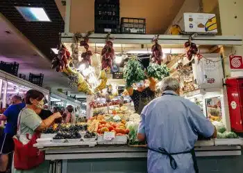 woman in white dress standing in front of vegetable display