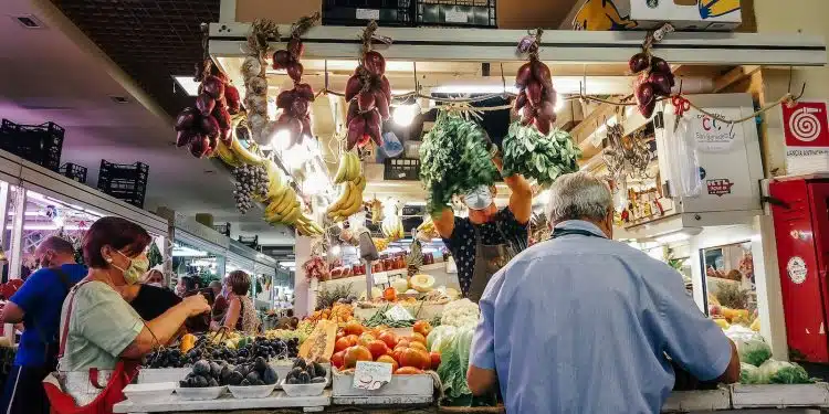 woman in white dress standing in front of vegetable display