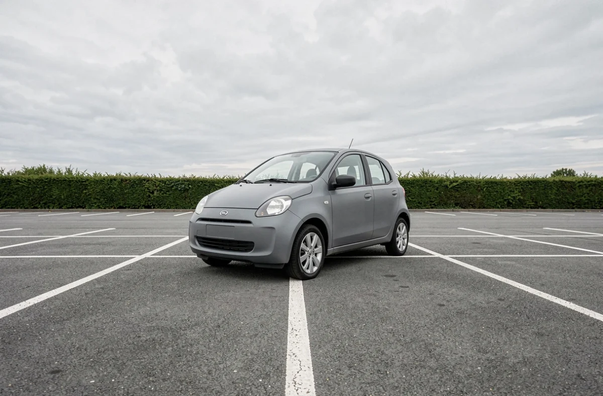 Voiture sans permis grise vue en angle bas dans un parking suburban avec lignes de marquage au sol
